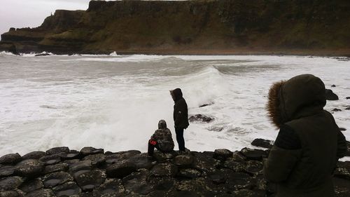 Friends at seashore against mountain