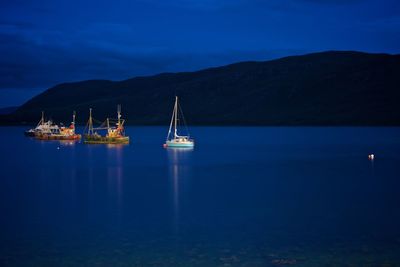 Sailboats in sea against sky at night