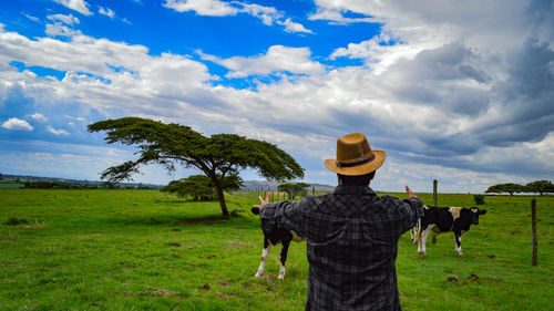 Rear view of man standing on field against sky