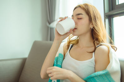 Young woman looking away while sitting at home