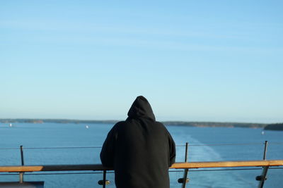 Rear view of man in sea against clear sky