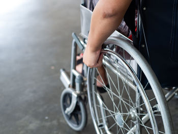 Low section of person sitting on wheelchair in city