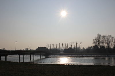 Silhouette bridge over river against sky in city