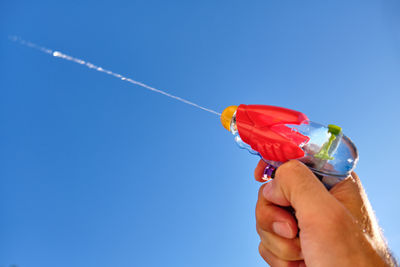 Low angle view of person holding umbrella against blue sky