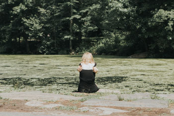 Rear view of woman sitting on swamp