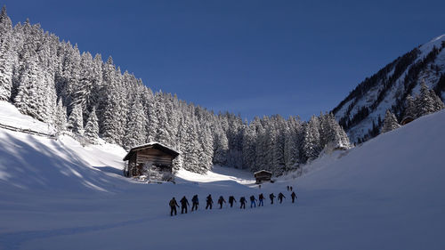 People walking on snow covered mountain against sky