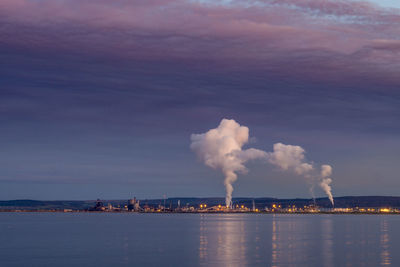 Smoke emitting from factory against sky