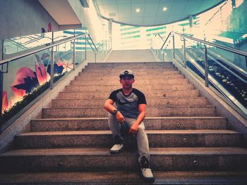 Full length portrait of young man sitting on staircase