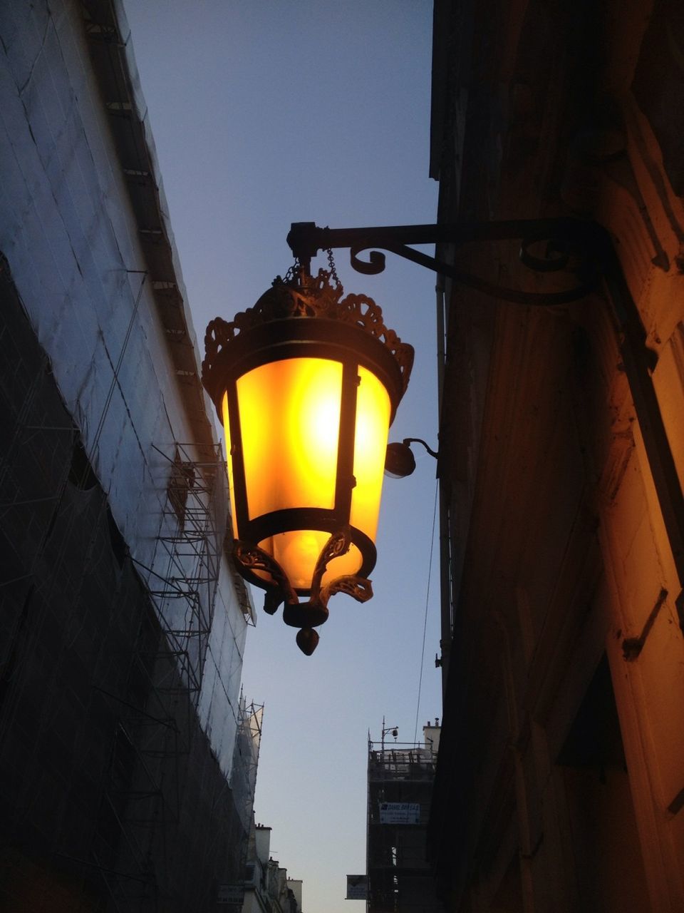 lighting equipment, illuminated, low angle view, street light, architecture, built structure, electricity, building exterior, electric light, lantern, electric lamp, lamp, light bulb, hanging, orange color, sunset, yellow, lamp post, night, sky