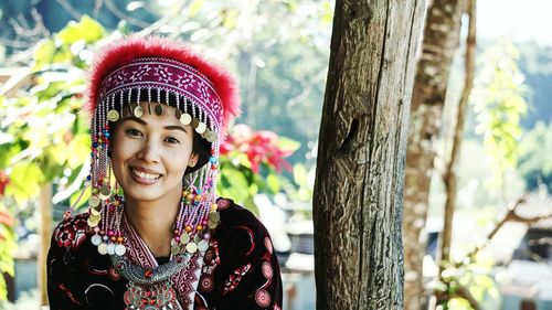 Portrait of smiling young woman against tree