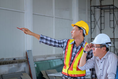 Architect pointing while explaining coworker at construction site