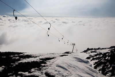 Overhead cable car over snow covered mountains against sky