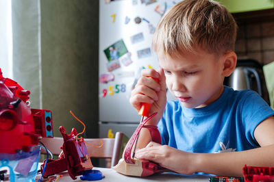 Close-up of boy takes apart toys with a screwdriver at home