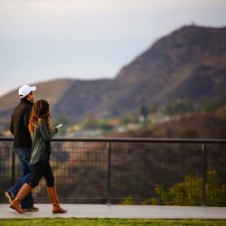 Side view of woman using phone while walking with friend on footpath