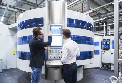 Two men talking in factory shop floor looking at screen