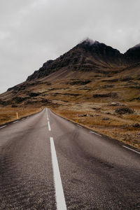 Road leading towards mountains against sky