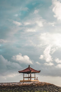 Low angel view of people by gazebo against sky