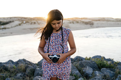 Full length of woman standing on rock in sea