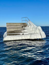 Boat floating on sea against clear blue sky