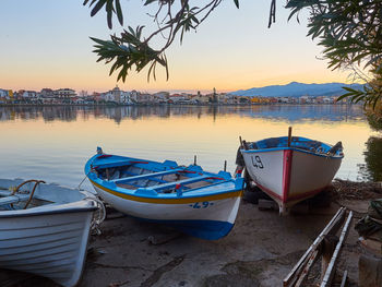 Boat moored at beach against sky during sunset