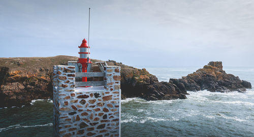 Lighthouse by sea against sky