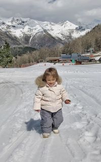 Portrait of girl standing on snow covered mountain in the snow clothes 