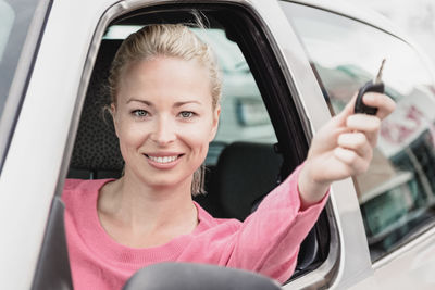 Portrait of young woman taking selfie while sitting in car