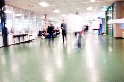 Defocused image of people walking in illuminated building