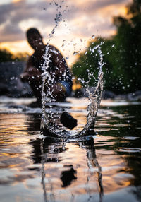 Close-up of water splashing on lake against sky during sunset