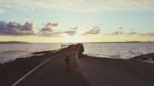 People at beach against sky during sunset