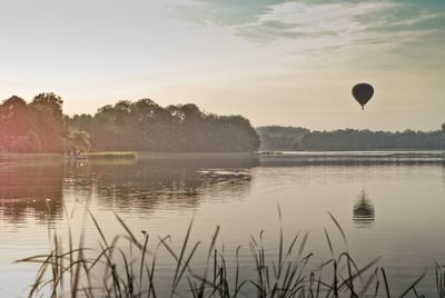 View of hot air balloon flying over calm lake
