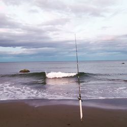 Scenic view of beach against cloudy sky