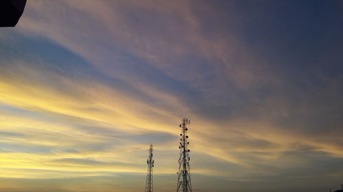 Low angle view of silhouette electricity pylon against sky during sunset