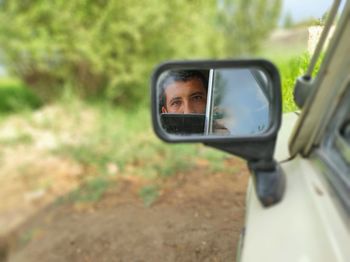 Portrait of man photographing on side-view mirror