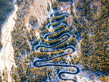 Aerial view of winding road amidst snow covered trees in forest