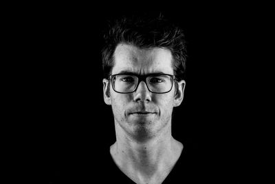 Portrait of young man against black background