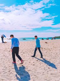 Full length of people on beach against sky