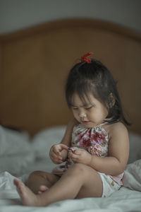 Cute baby girl sitting on bed at home