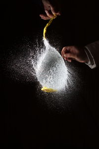 Midsection of person splashing water against black background