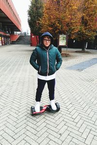 Portrait of boy on hoverboard standing on footpath