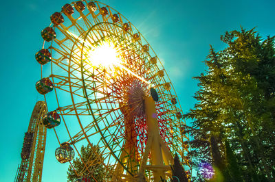 Low angle view of rides at amusement park against sky on sunny day