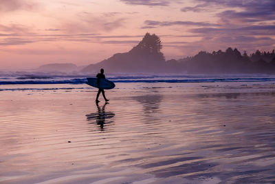 Man on beach against sky during sunset