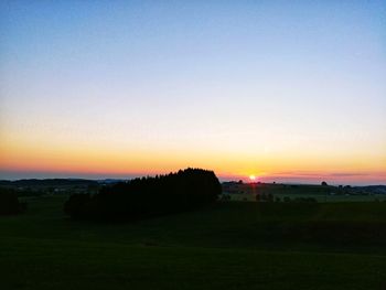 Scenic view of field against clear sky during sunset