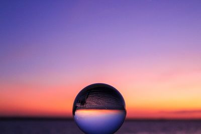 Close-up of water ball against clear sky during sunset