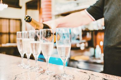 Cropped image of bartender pouring wine in glasses at bar