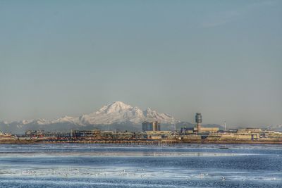 Built structure by sea against clear sky during winter