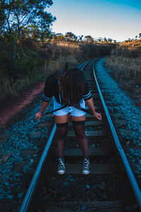 Full length of woman standing on railroad tracks during sunset