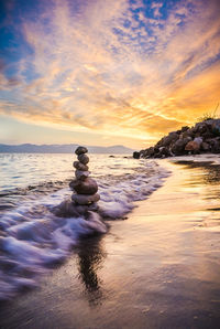 Stacked rocks hit by a wave at sunset