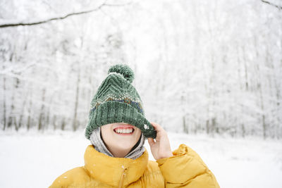 Happy boy having fun covering face with knit hat at park