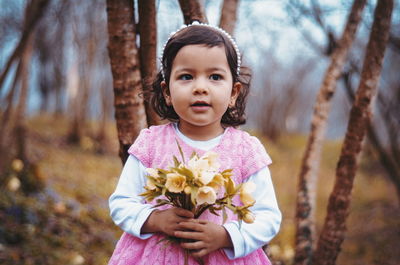 Innocent girl holding flowers on field